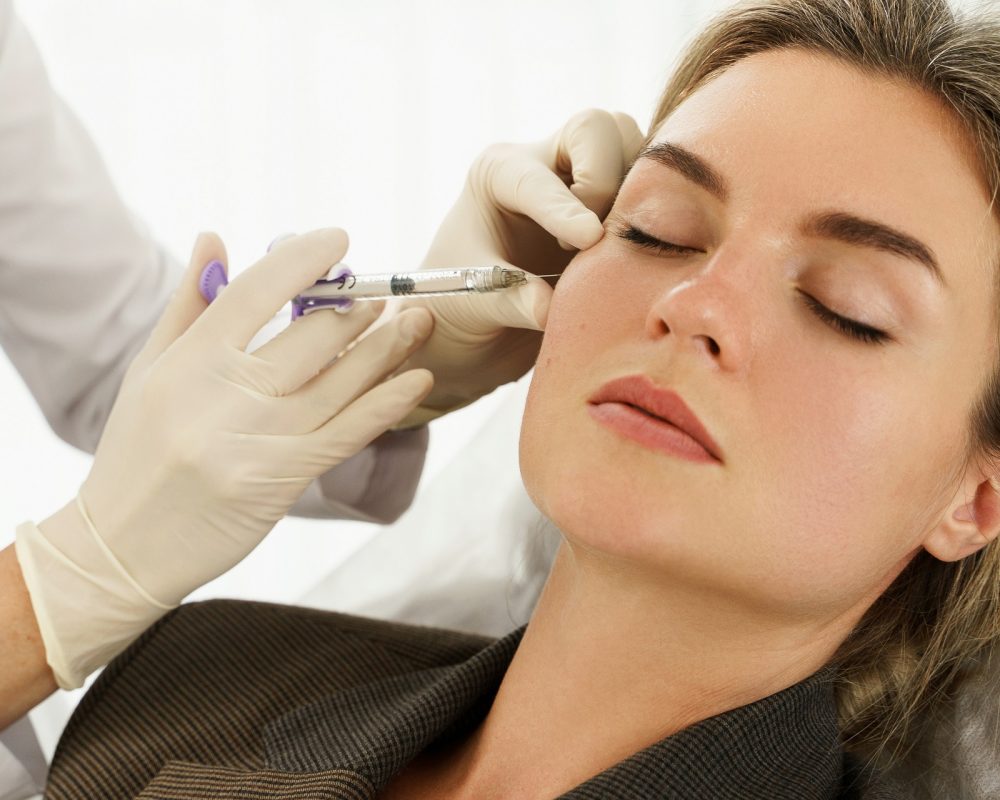Female client during facial filler injections in aesthetic medical clinic in New York, NY | HitSpa